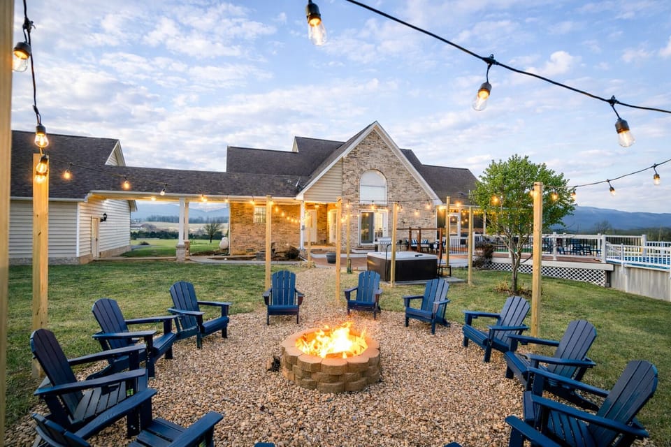 Cozy twilight firepit circle with Adirondack seating, string lights, and hot tub nearby—an inviting outdoor hangout where your group can toast s’mores, swap stories, and soak in the mountain air.