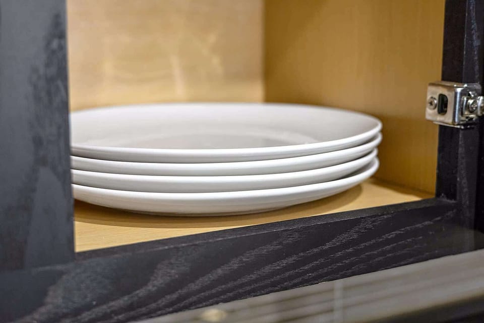 Cabinet filled with plates and dinnerware to support meals of any size, from quick bites to full dinners.