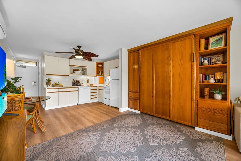 Enjoy a spacious open layout with warm wood cabinetry, a cozy dining area, and a well-equipped kitchen accented by tropical décor.