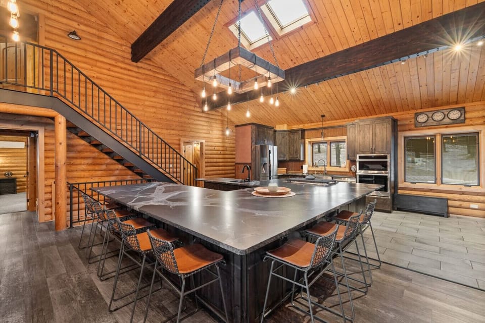 Prepare to be wowed by the enormous central kitchen island, which comfortably seats everyone and serves as the ultimate gathering spot under dramatic lighting.