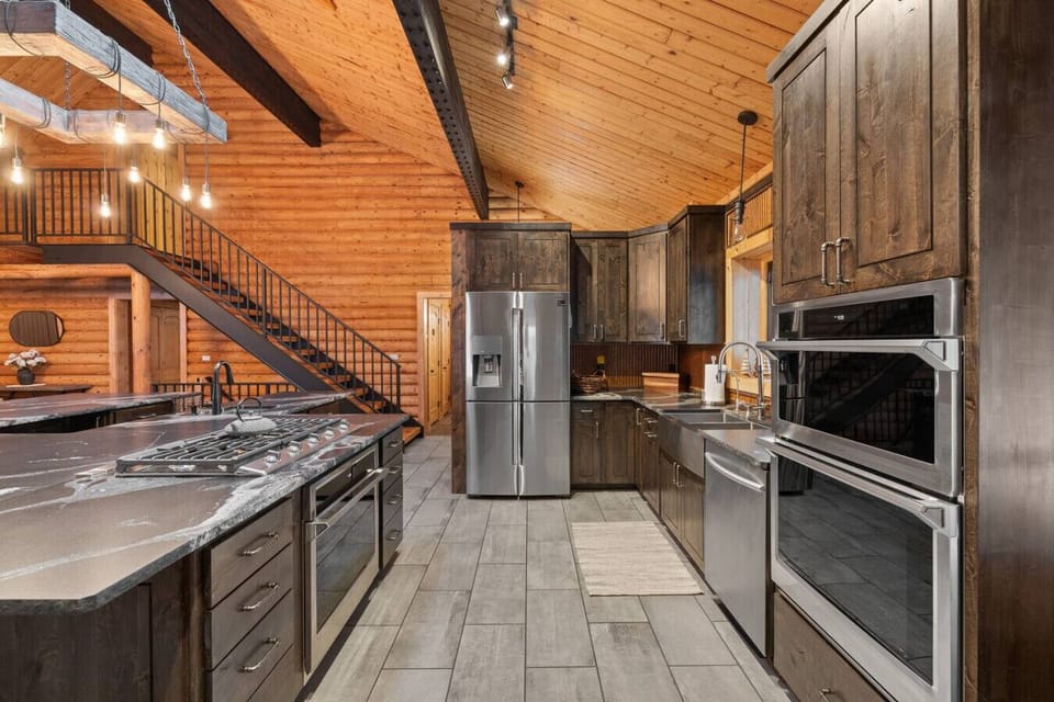 Discover a magnificent kitchen designed for the discerning traveler, featuring high-end appliances and striking dark stone surfaces across multiple prep stations.