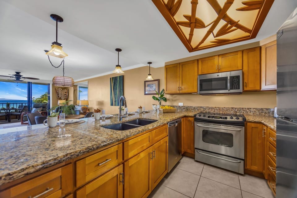 Modern kitchen with granite counters, wood cabinetry, and ocean views.