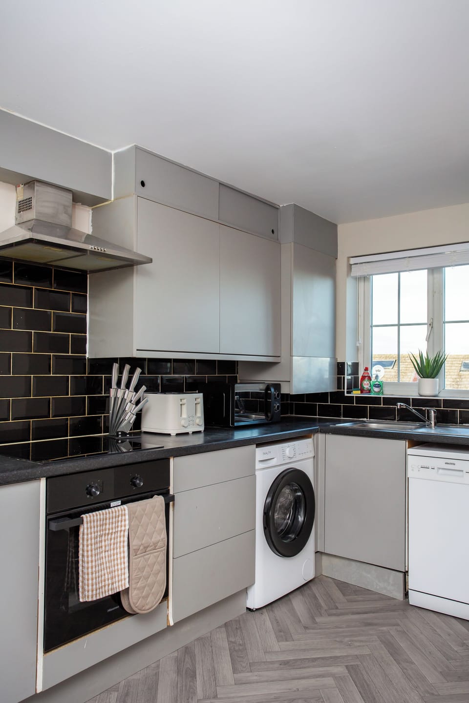 Fully equipped kitchen featuring oven, hob, microwave, and washing machine.
