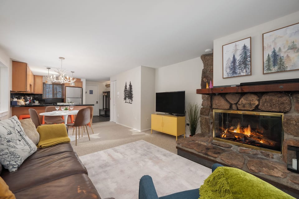 Cozy up by your crackling stone fireplace while enjoying the open-concept living space with mountain-inspired decor and fully equipped kitchen.