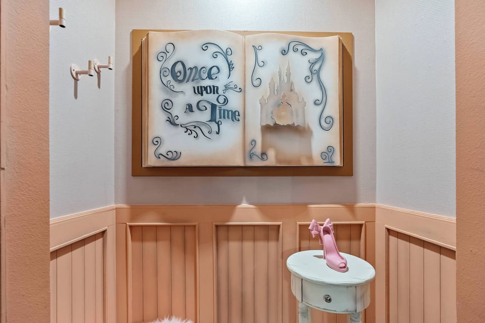 Enter a whimsical entryway featuring charming wall art that says "Once Upon a Time," surrounded by soft pastel hues and playful accents. The unique table and delightful pink decor ensure your arrival feels truly special.