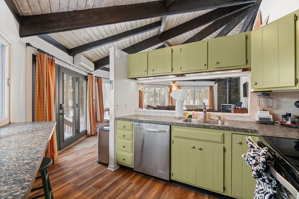 Bright kitchen with retro green cabinets and natural light in Lake Naomi cabin rental