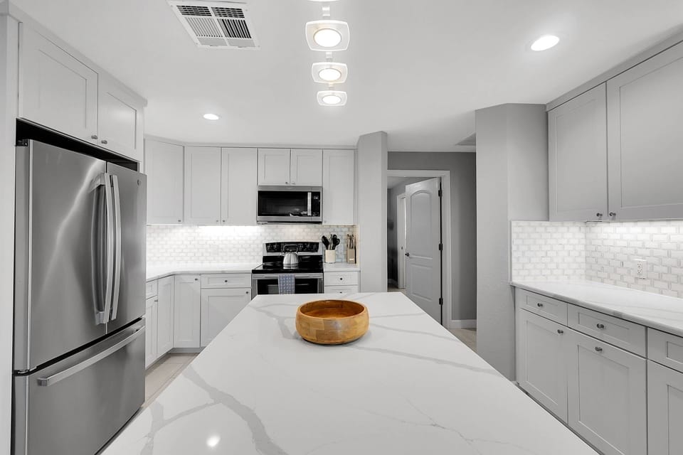The bright, modern kitchen, offers upgraded appliances, plenty of storage, elegant quartz countertops, and a striking designer backsplash.