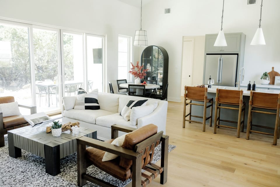 Sunlit living room with leather chairs, patio access, and chic dining
