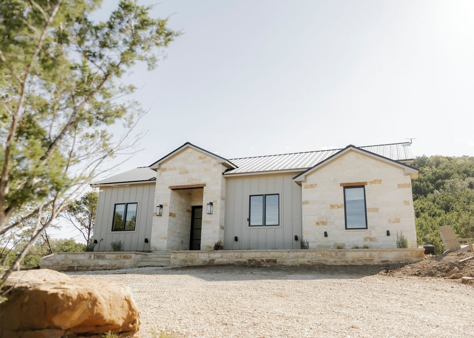 Modern stone farmhouse with metal roof and views in quiet hill country

