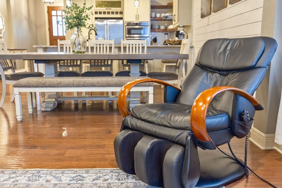 Relax in your own massage chair overlooking the open dining and kitchen area. A perfect spot to unwind while enjoying the warm, inviting atmosphere of this beautifully designed home.