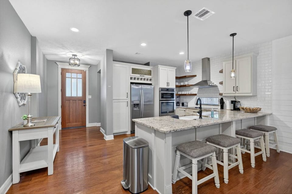 Bright and modern kitchen with granite counters, stainless appliances, and bar seating for four. A welcoming entryway and open layout make cooking and gathering easy and enjoyable.