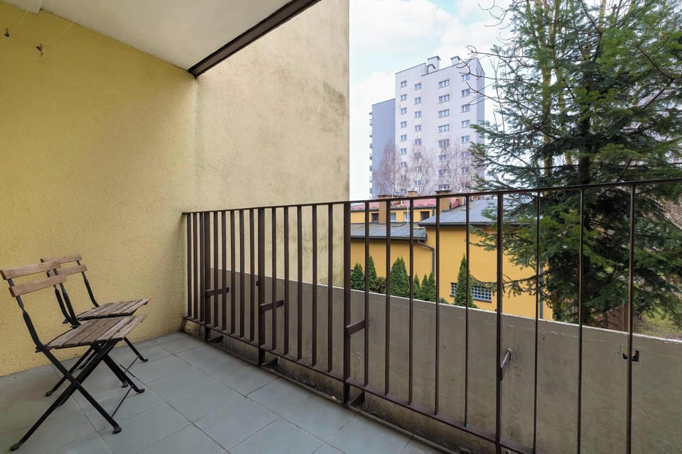A balcony with outdoor seating and a view of surrounding buildings. It’s a peaceful spot to relax outside.
