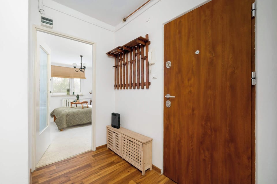 A hallway view facing the entrance door with wooden finishes. The space is clean, minimal, and well organized.