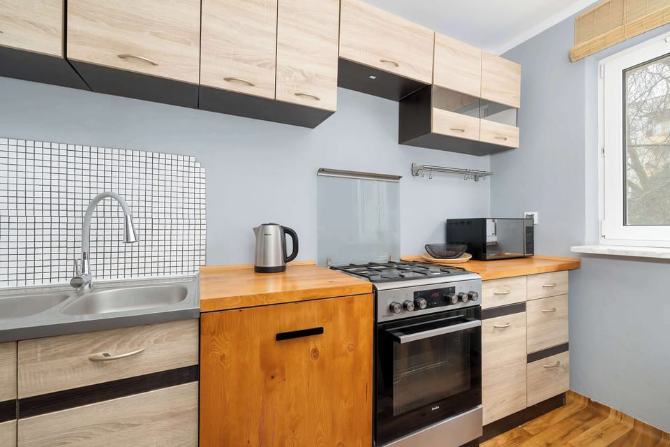 A kitchen space with built-in appliances, wooden cabinetry, and a small dining table. The layout is convenient for cooking and eating.