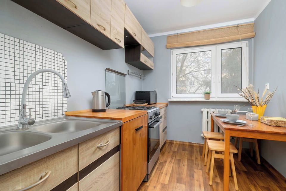 A compact kitchen with wooden cabinets and a cozy dining corner. Natural light enhances the warm tones of the interior.