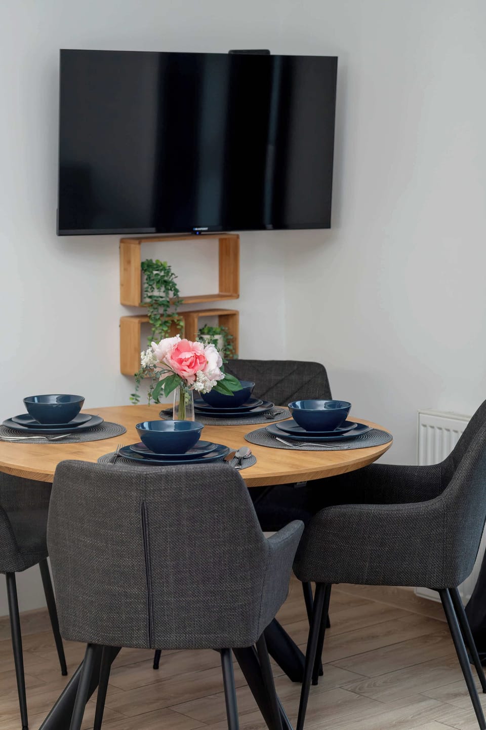 The neatly set table beneath the TV creates a spot where guests can enjoy meals while watching their favourite entertainment.
