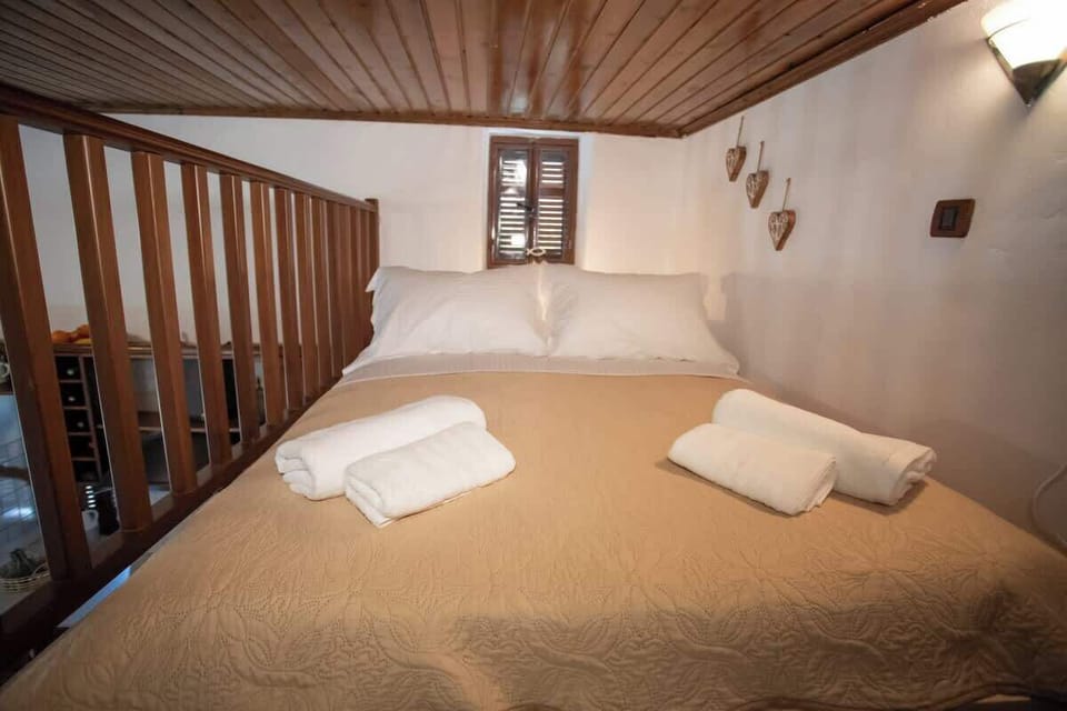 Loft bedroom with soft lighting, a wooden ceiling, and a comfortable double bed, creating an intimate and tranquil sleeping space that blends rustic charm with peaceful comfort.
