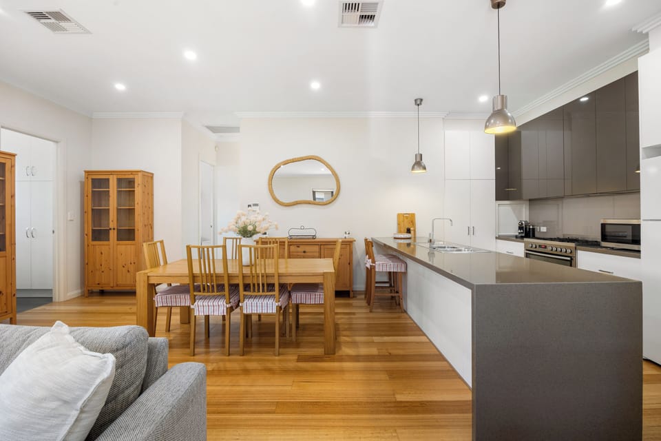 A large timber table offers an inviting setting for shared dishes, morning coffee or planning the day in this open-plan layout.