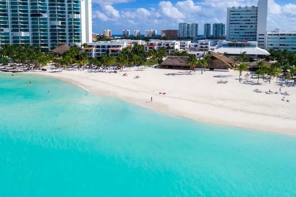 Wander barefoot along the wide white-sand shoreline at sunset.