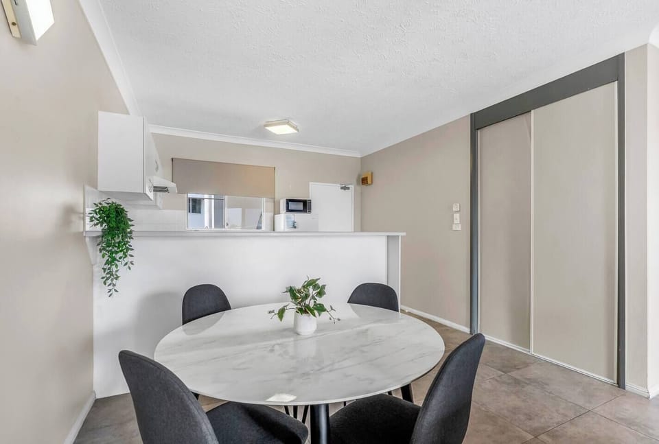 The round table welcomes shared meals, comfortable conversation and a clear view toward the leafy balcony.