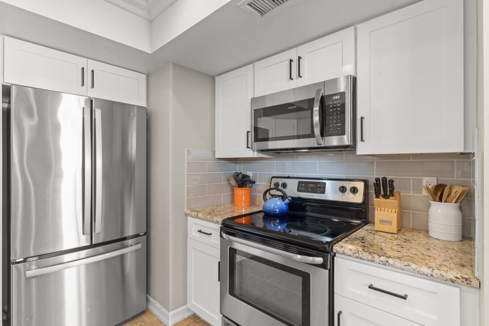 Modern stainless steel appliances including full-size refrigerator, gas range, and built-in microwave for convenient everyday cooking.