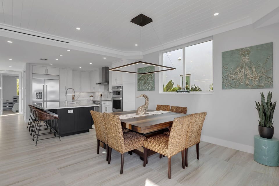 The inviting dining area features a stylish table with seating for eight, complemented by an additional four seats at the kitchen island—perfect for family meals and casual gatherings.