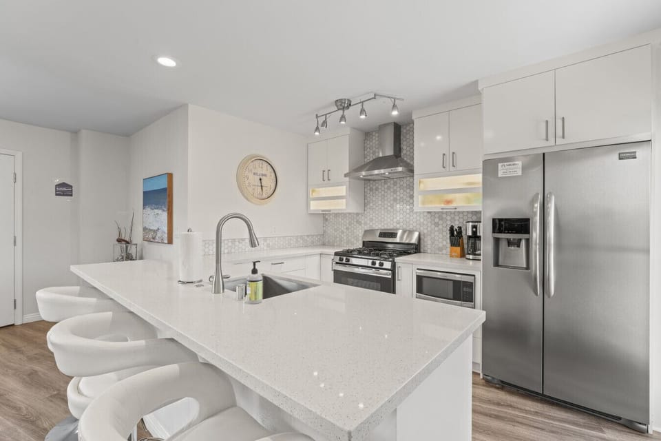 Sleek kitchen w/ quartz island seating & stainless appliances for easy cooking