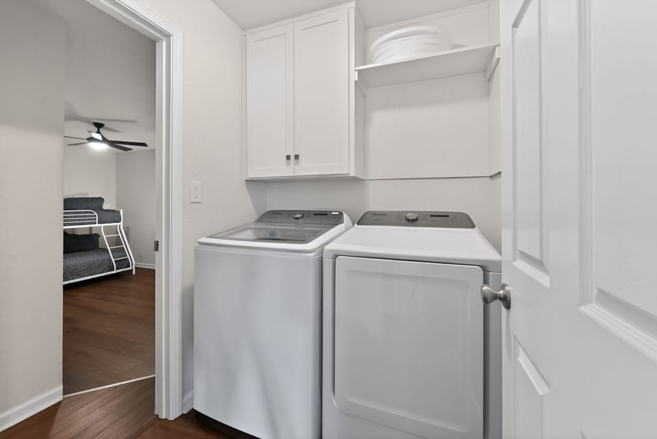 A laundry nook equipped with a washer, dryer, and overhead cabinetry.
