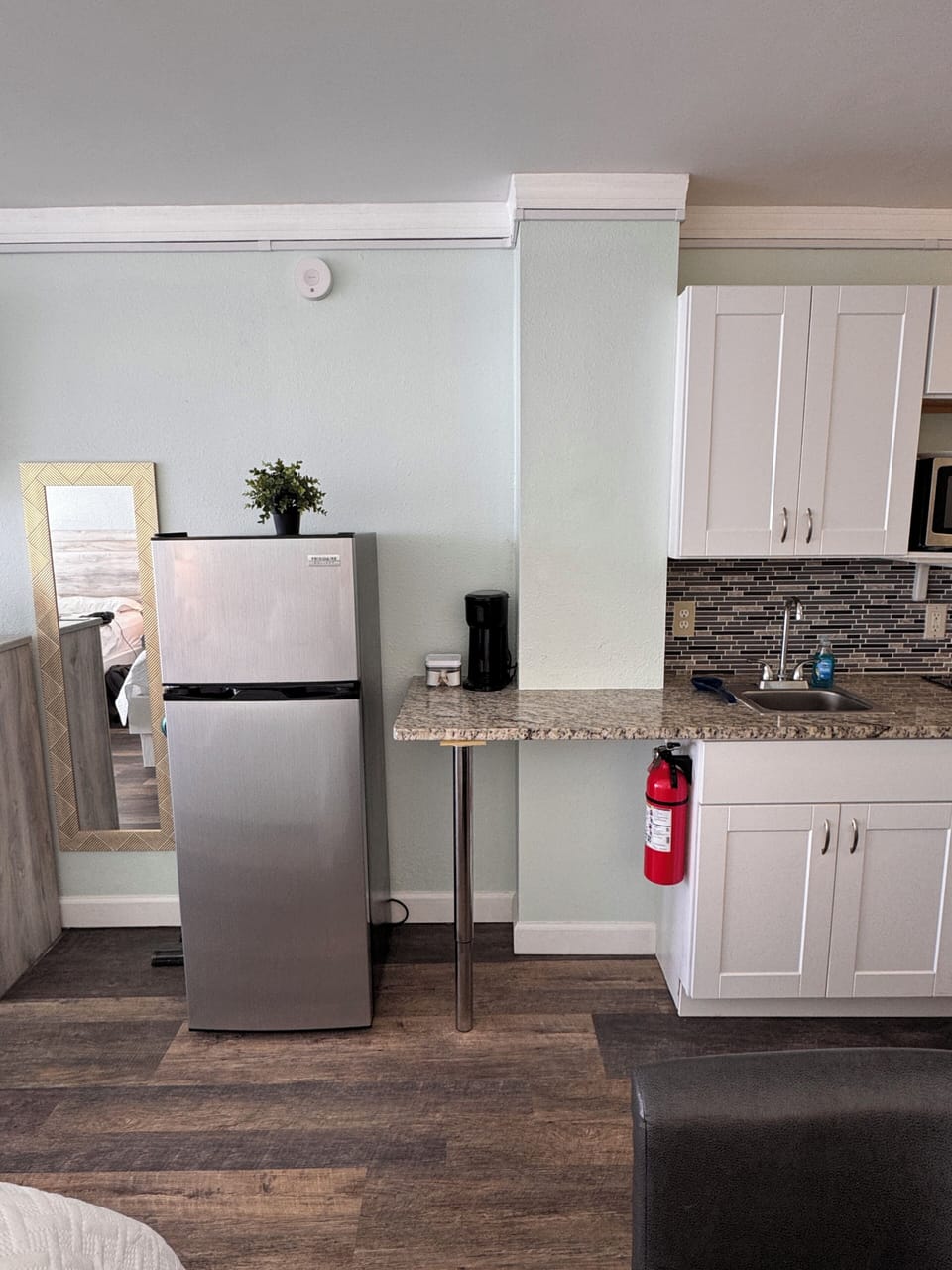 Sleek kitchenette: stainless fridge, granite tops & coffee setup
