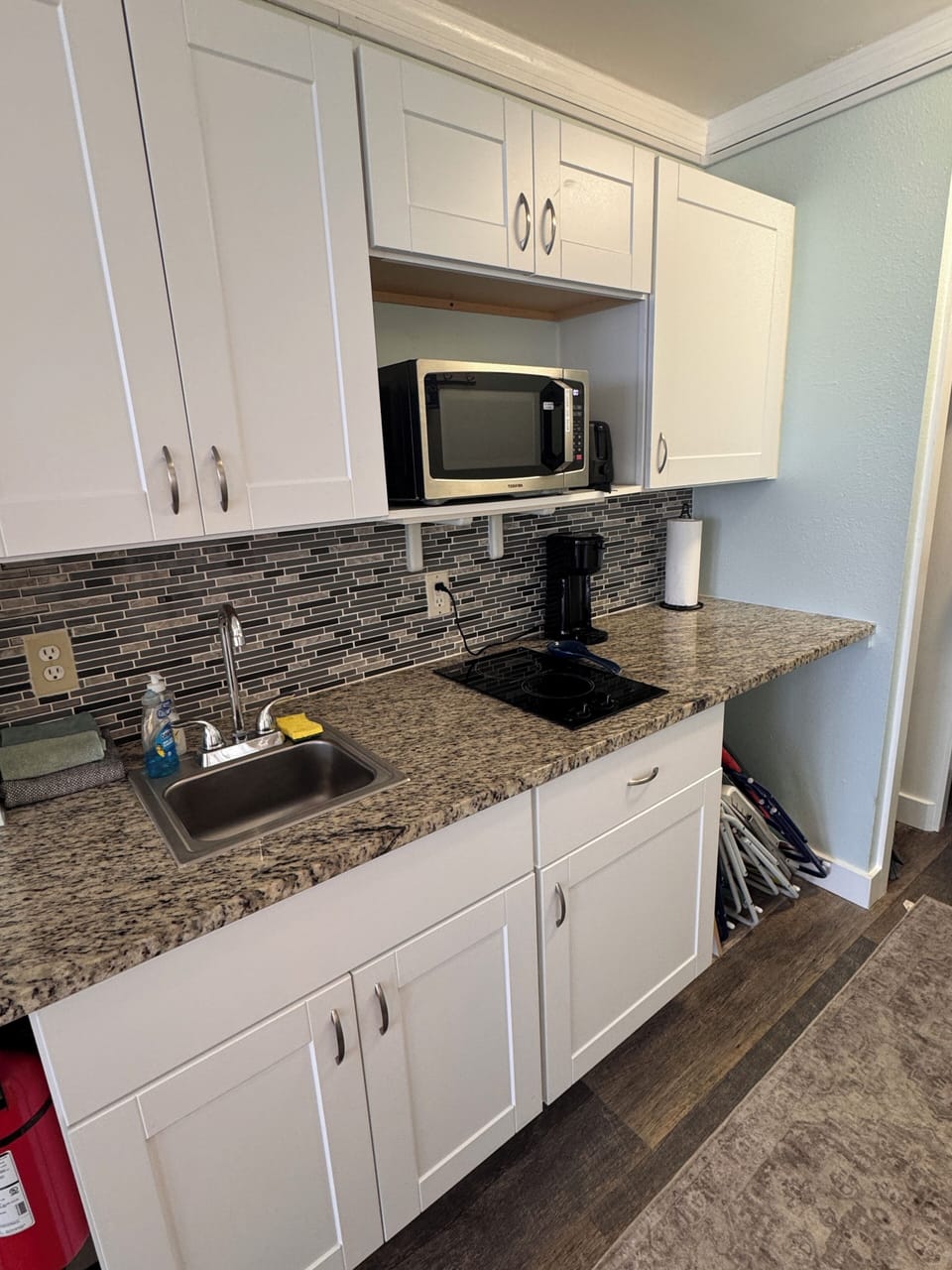 Modern kitchenette with granite counters, cooktop, and coffee station