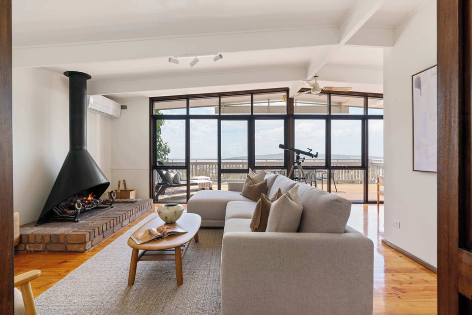 Light-filled lounge room, with open fireplace, cosy seating and views
