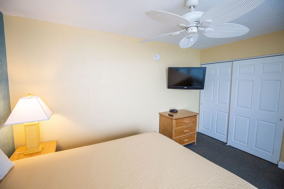 Relax in the cozy bedroom featuring a comfortable bed, a modern flat-screen TV, and ample storage space, perfect for unwinding after a day at the beach.