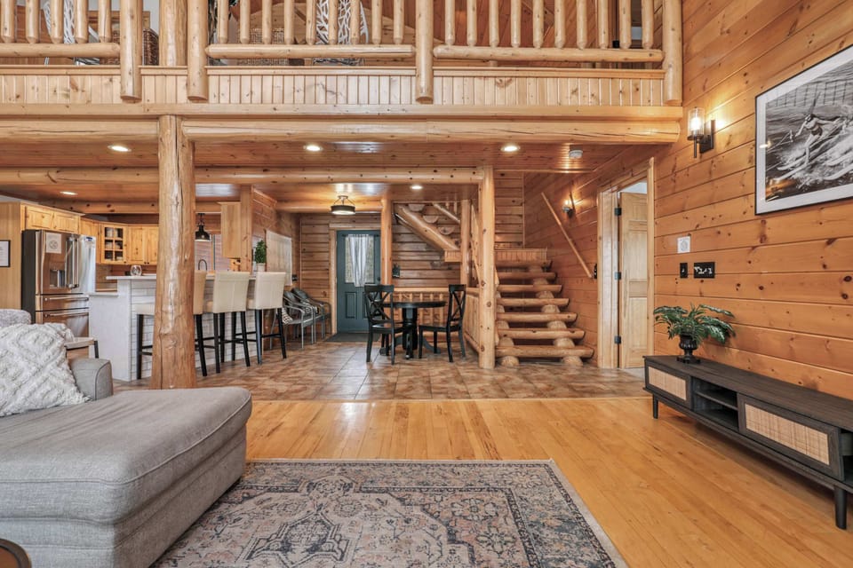 Our luxury log cabin living room features a large sectional, 65" smart TV, gas fire place, walkout access to the front deck, and an open concept into the dining and kitchen area. We have dining seats for 18.