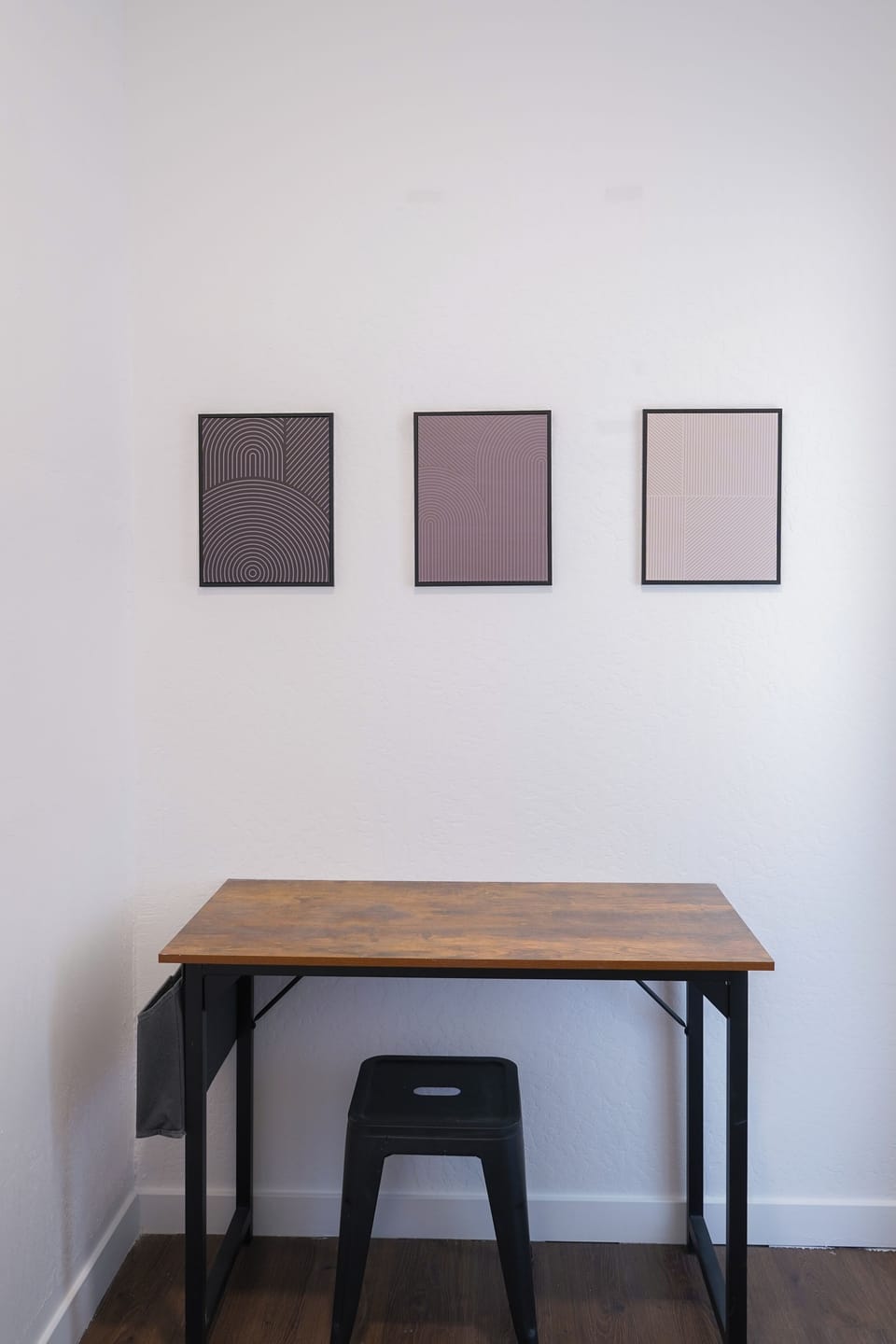 Office space with wood desk, matching stool, and art displayed above.