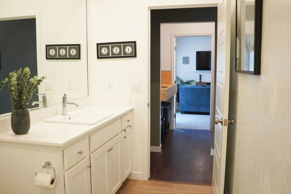 Bathroom with large counter and sink, hallway leads to kitchen and living room.