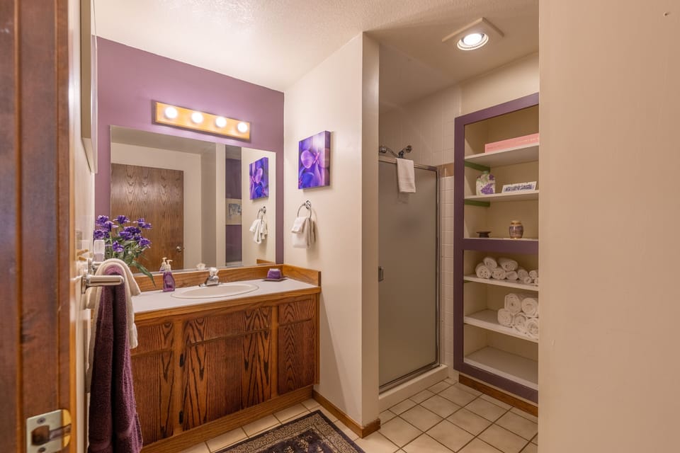 Bathroom featuring a wood vanity, purple accent wall, and built-in open shelving.