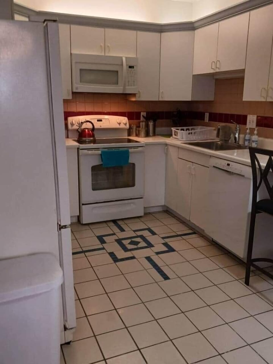 Here is the right side of the kitchen.  Refrigerator, stove, sink, dishwasher all visible.
