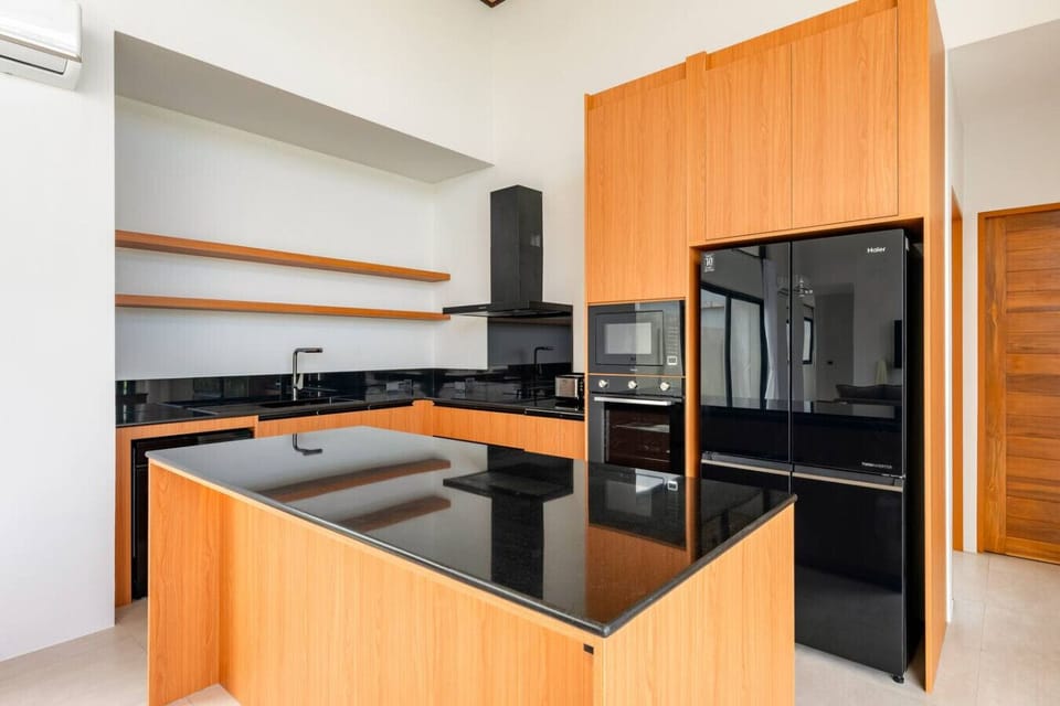 Modern fully-equipped kitchen with orange cabinets, island, sleek appliances - contemporary Green Garden Villa