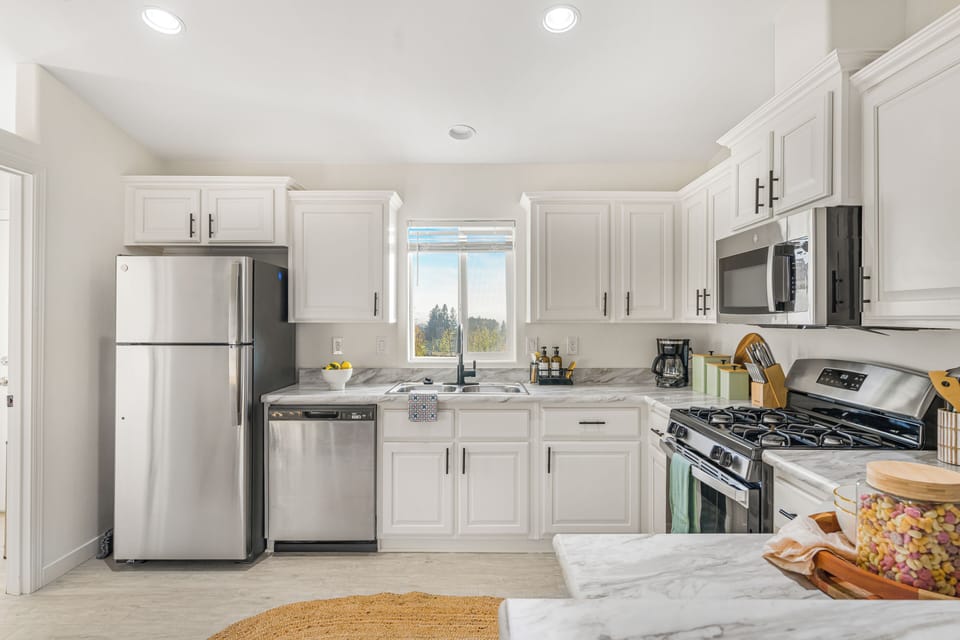 Kitchen view showing the stainless steel refrigerator, white cabinets, and gas range.