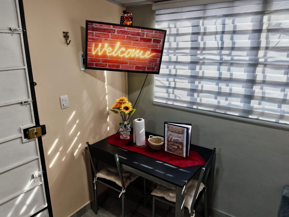 Comedor con mesa para dos, Smart TV y luz natural.