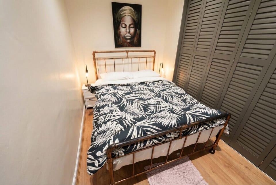 A closer view of the copper-framed double bed with matching bedside lamps and a large framed artwork mounted above the headboard.