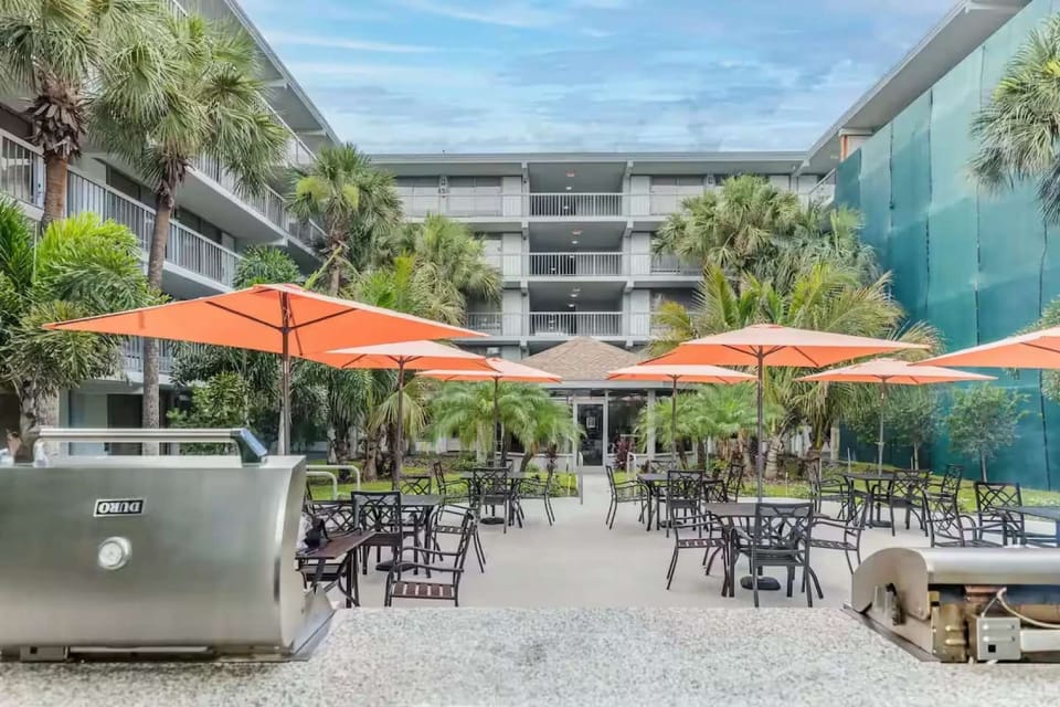 Outdoor Dining Area – Tables under orange umbrellas with BBQ grills