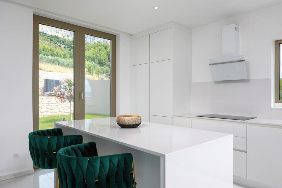 The modern kitchen features an island with high-end appliances and offers views of the natural surroundings.
