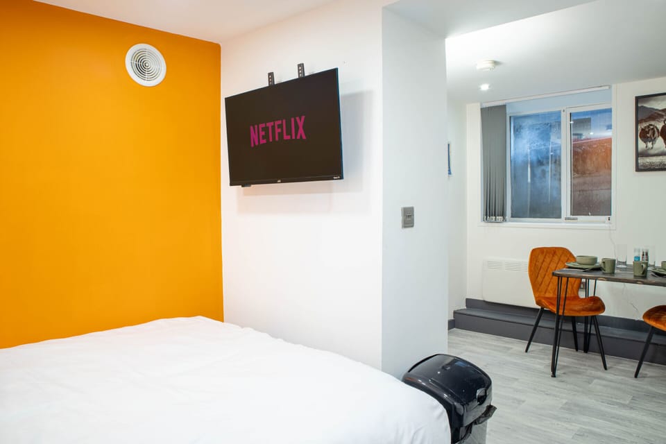 Sleeping area with comfortable double bed, crisp hotel-quality linen, and wall-mounted smart TV with Netflix.