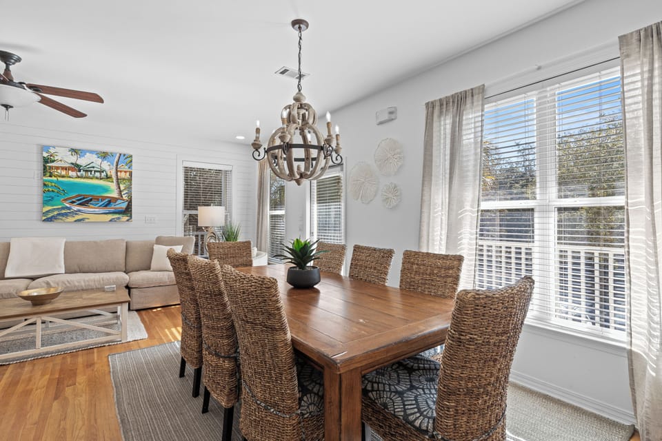 Gather around this beautiful wooden dining table with wicker chairs, where natural light floods through large windows creating the perfect space for memorable meals.