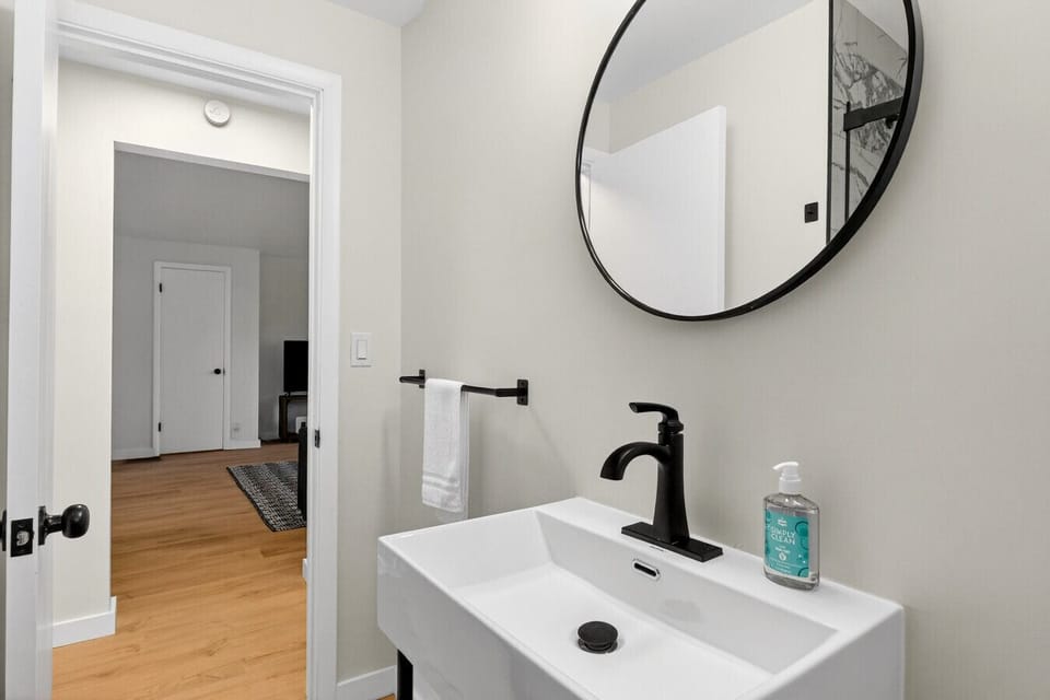 Updated bathroom vanity with round mirror and modern fixtures.