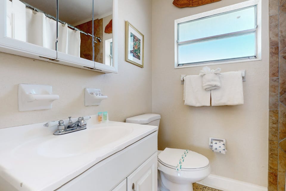 This bright bathroom is ideal for your beach stay, featuring a clean vanity, fresh towels, and a relaxing shower. A convenient space to refresh and unwind after sandy beach days.