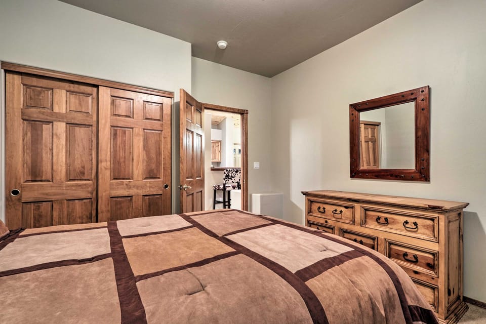 A bedroom with a rustic wooden dresser, mirror, and paneled closet doors.
