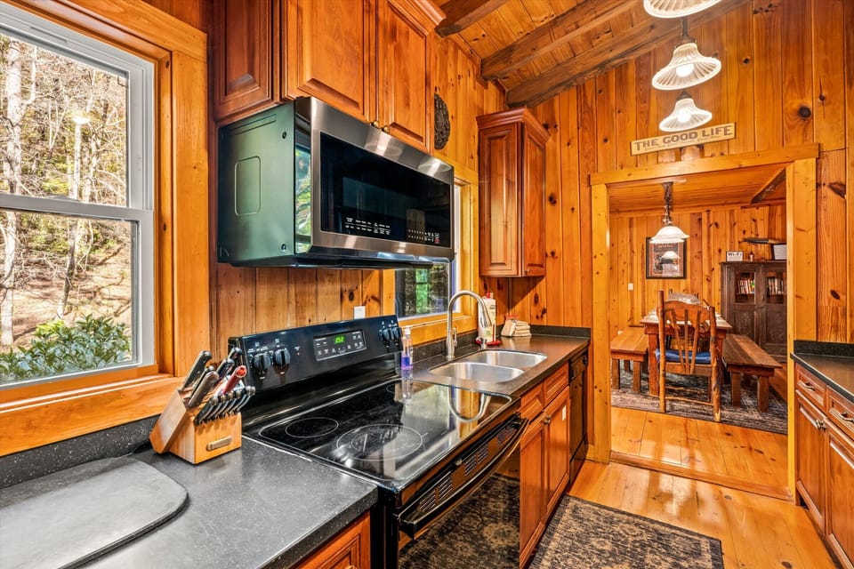 This warm, cabin-style kitchen features rich wood cabinetry, modern appliances, and peaceful woodland views—perfect for cooking and gathering in true mountain comfort.