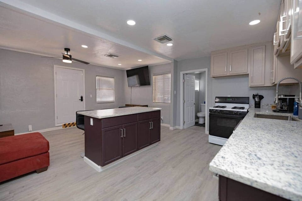 Kitchen and living room areas, including 65" Smart TV. Kitchen island offers built-in USB charging port and auto night-light